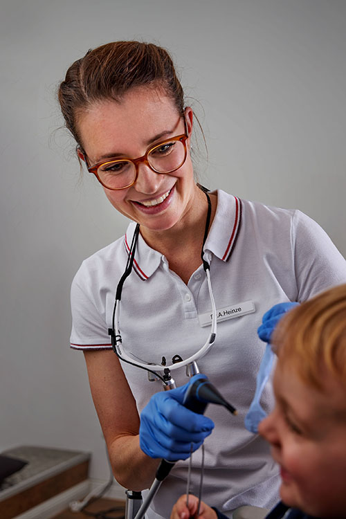 Dr. Alessandra Heinze im weißen Poloshirt mit einem lachenden Kind auf dem Behandlungsstuhl